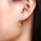 Fine jewellery, silver jewellery plated with rose gold, hypoallergenic, tarnish-free, Close-up left view of an ear wearing a rose gold hoop earring with a blurred background